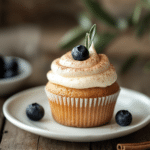 Cupcake – The 1 Ultimate Guide to Meaning, History, and Delicious Recipes 7 Keto vanilla cupcake topped with cream cheese frosting and a blueberry on a white plate