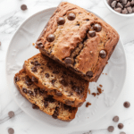 Chocolate Chip Banana Bread (Moist, Easy & Full of Chocolate!) 5 sliced chocolate chip banana bread on a white plate, golden crust and melted chocolate chips, styled for recipe card with clean background