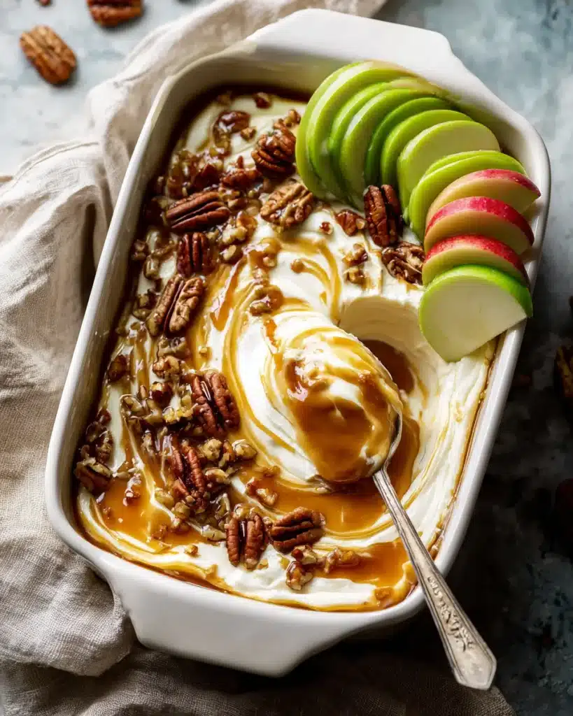 Easy Caramel Apple Cheesecake 2 Caramel apple cheesecake dip with spoon and apple slices in white dish