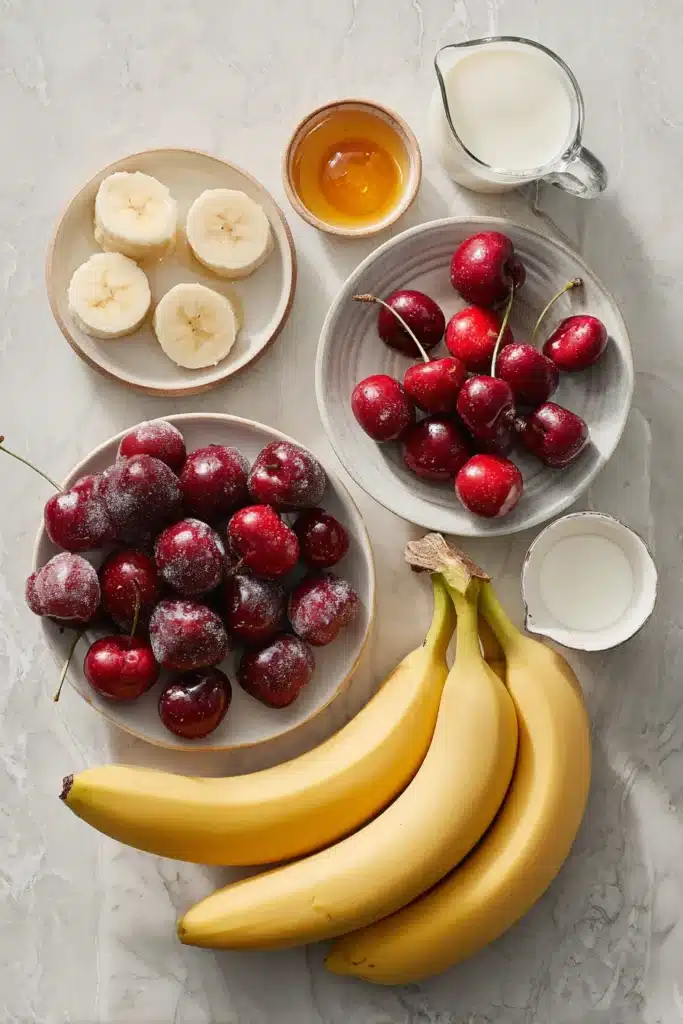 Banana cherry smoothie ingredients with frozen cherries, banana, yogurt, milk, and honey