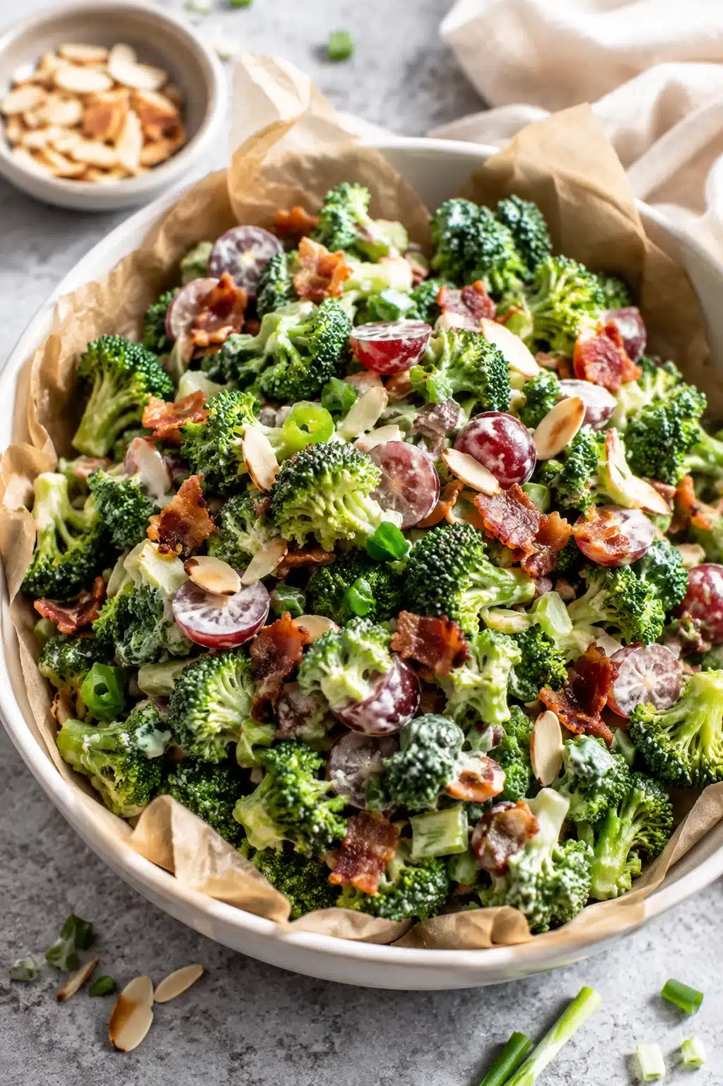 Fresh Broccoli Salad with Bacon, grapes, almonds, and creamy dressing in a rustic serving bowl.
